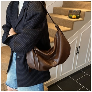 Deep brown oversized slouchy hobo bag shown worn on shoulder by model on stairs