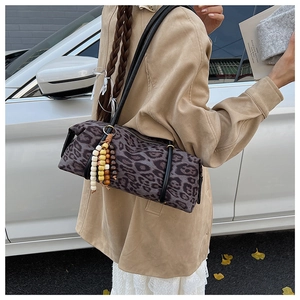 Leopard print barrel bag with wooden bead tassel shown in an autumn street setting