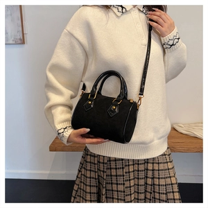 Detail of black quilted suede Boston bag with patent leather trim and gold hardware