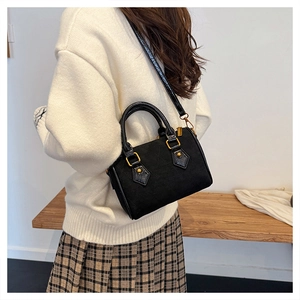 Detalle de bolso bandolera de ante negro acolchado con asas de cuero brillante