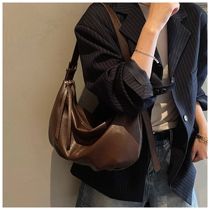 Dark brown hobo bag with long tassel detail worn by a model in casual office attire
