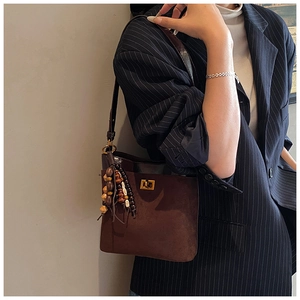 Detail of vintage brown suede bucket bag with metal twist lock and wooden bead accessory