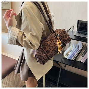 Detail of retro leopard print barrel bag with colorful beaded tassel and slim straps