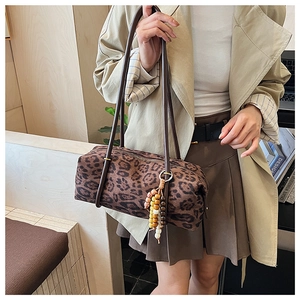 Detail of leopard print cylinder bag with beads charm shown on a model's shoulder