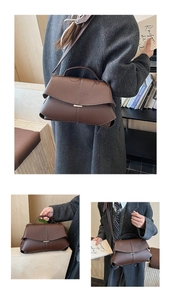 Detail of dark brown leather handbag with gold metal clasp and adjustable shoulder strap