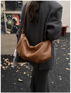 Deep caramel brown semi-moon tote bag with elegant side fringe tassel and soft leather texture