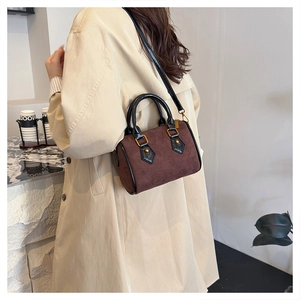 Detail of dark brown suede pillow bag with diamond stitching and gold hardware on model