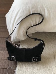 Minimalist black suede hobo bag with silver buckle straps and adjustable shoulder handle