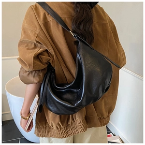 Detailed side view of black crescent tote bag showing supple leather texture and large capacity