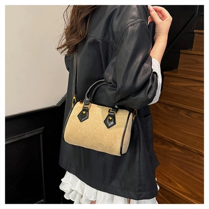 Detailed view of khaki suede boston bag with white quilted stitching and black leather straps