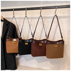 Detail of suede bucket bags in brown, black and olive with gold metal twist-lock clasps