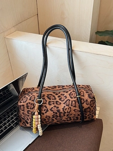 Retro leopard print shoulder bag with black handles and beaded charm on wooden background