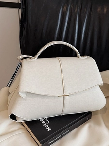 Elegant cream textured leather handbag with gold metal accents and top handle design