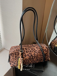 Retro leopard print cylinder shoulder bag with ethnic beaded tassel charm on a book