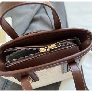 Detail of metal zipper and leather trim on a contrast color tote bag for women