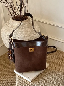 Vintage brown suede bucket bag with gold clasp and wooden bead charm in a retro style
