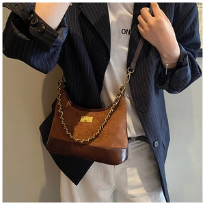 Retro quilted brown suede crossbody bag with gold chain worn on a striped blazer