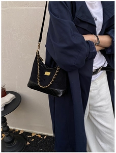 Quilted black leather handbag with gold chain detail and turn-lock shown on a model