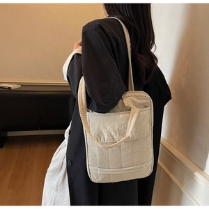 Detail view of large beige quilted tote bag showing smooth polyester texture and spacious pockets