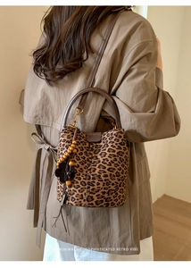 Nahaufnahme der Retro-Beuteltasche mit Leopardenmuster, Ledergriff und Blumenanhänger