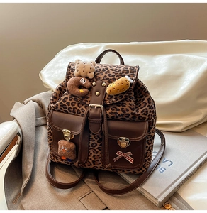 Detail of leopard print backpack with plush charms and premium leather trim accents