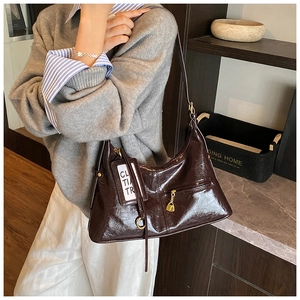 Detailed shot of dark brown glossy leather bag with gold hardware and logo tag