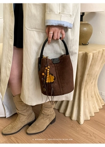 Detail der dunkelbraunen Wildleder-Eimertasche mit Holzperlenanhänger und Griff