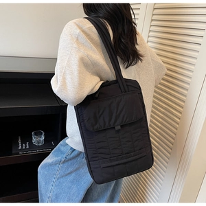 Borsa tote trapuntata nera indossata dal modello per un look da ufficio chic