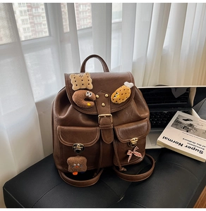 Detailed view of brown PU leather backpack with cute plush biscuit charms and bow