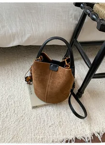 Detail der braunen Wildleder-Beuteltasche mit Holzperlen und Blumen-Anhänger