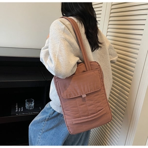 Detailed view of large quilted brick red tote bag used as a stylish laptop commuter bag