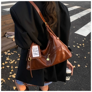 Caramel brown patent leather tote bag styled with a black blazer on an autumn street