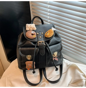 Detail of black PU leather backpack with gold buckles and cute plush cartoon patches