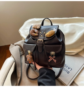 Detail of dark brown PU leather backpack featuring cute plush brooches and plaid bow detail
