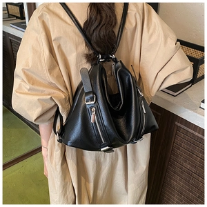 Detail of black pebbled leather backpack with silver zippers on model back
