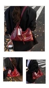 Detail view of burgundy patent leather bag with gold hardware on autumn street