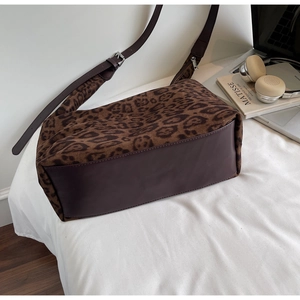 Detail of leopard print tote bag with brown leather base and metallic zipper