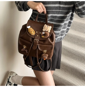 Detail of vintage brown leather backpack with cute plush charms and bow side pockets