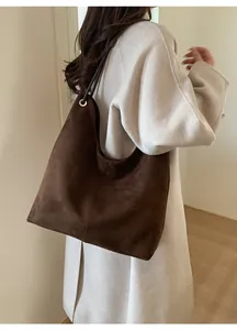 Detailed view of coffee brown suede tote bag featuring metallic grommets and soft texture