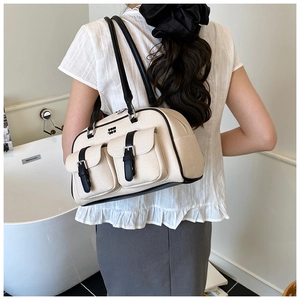 Chic cream woven shoulder bag with black trim worn by a model in a minimalist setting