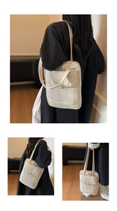 Detail of multi-pocket off-white shoulder bag with quilted texture and long handles