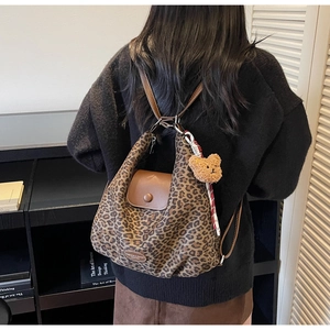 Detail of leopard print backpack with brown leather flap and cute plush bear charm
