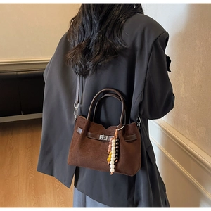 Dettaglio della borsa a tracolla in camoscio marrone scuro con ciondolo boho e chiusura