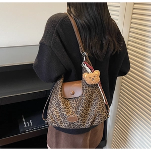 Detailed view of leopard print tote bag with leather flap and plush bear charm