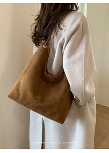Brown suede hobo tote bag with vertical stitching shown on model in minimal setting