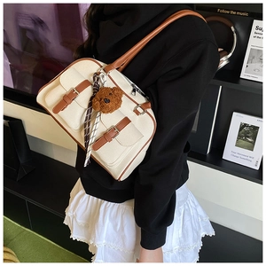Detail of vintage canvas pillow bag with contrast faux leather trim and cute bear charm