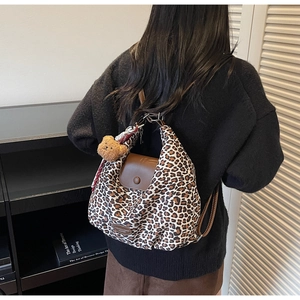 Close-up of leopard print tote with leather flap and a cute brown bear plush charm