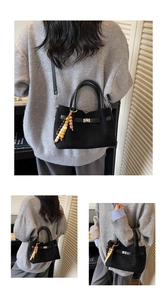 Detalle de bolso shopper negro mate con colgante de cuentas de madera y cierre de hebilla
