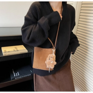 Sac seau en daim marron avec un pendentif ours en peluche dans une scène de style