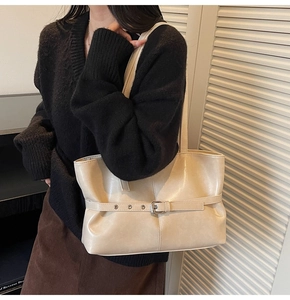 Détail de la boucle décorative et de la texture en cuir mat d'un sac cabas beige